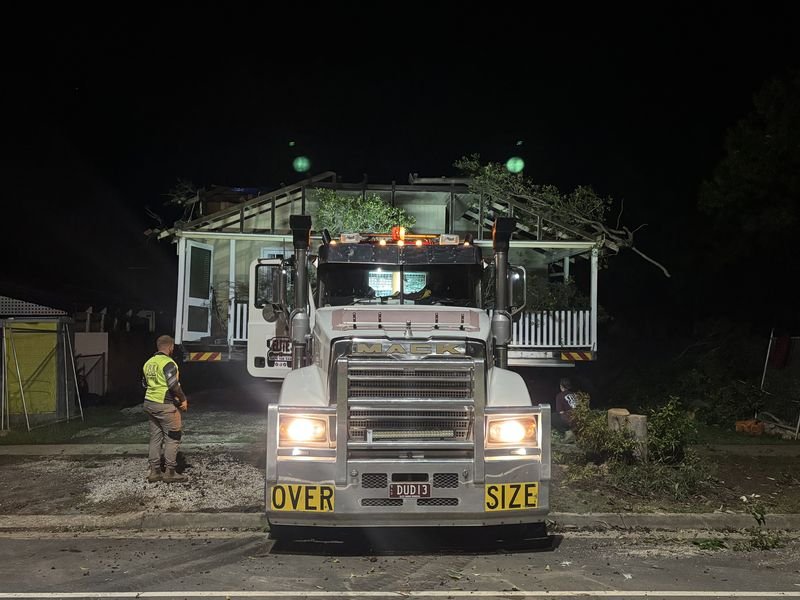 Oversize load truck carrying a house at night